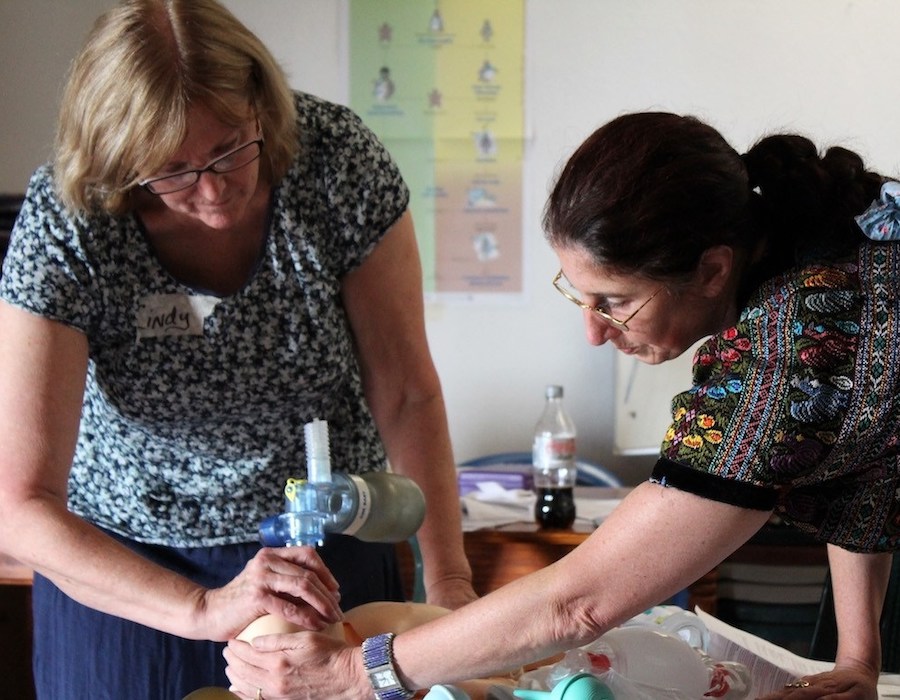 medical person showing a volunteer how to help newborns start breathing