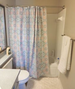 bathroom with shower curtain, white towels and rug